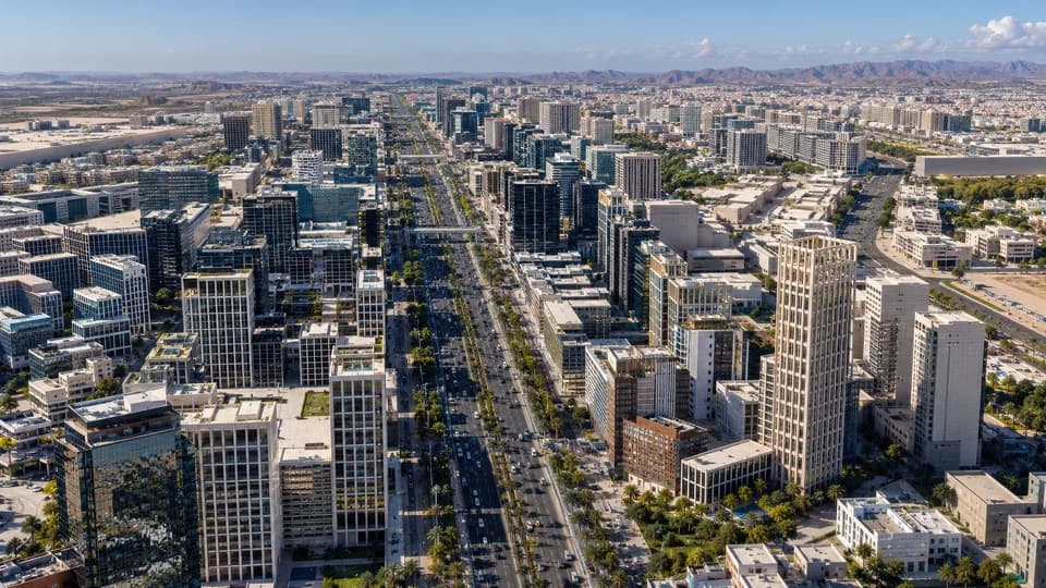 Aerial view of a large arrival plaza and radial street grid framed by low stone-clad buildings.